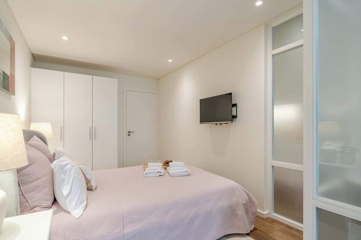 Een slaapkamer met een bed, een aan de muur bevestigde televisie en een kledingkast.