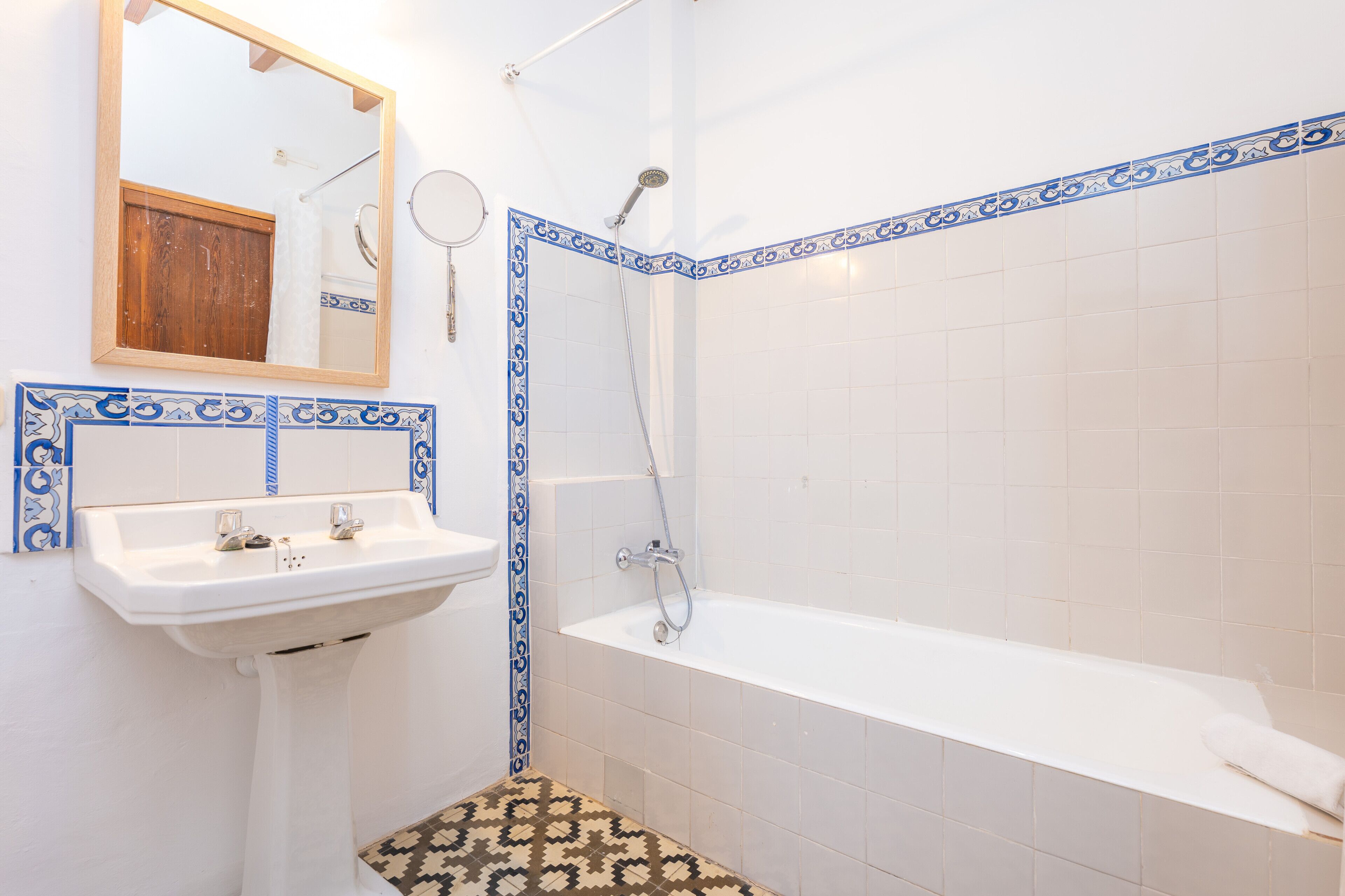 A bathroom with a sink, mirror, and bathtub.