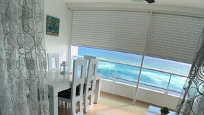 Un balcon avec vue sur l’océan, un ventilateur de plafond et un coin repas avec des chaises et une table.
