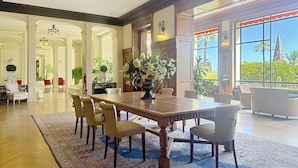 A spacious dining area with a large wooden table surrounded by chairs, a patterned rug, and a vase of flowers. - Studio l`Atelier – Parking & Beaches 15 min Walk (Cannes)