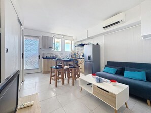 Una cocina moderna con comedor, sofá y televisor.