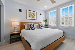 A bedroom with a bed, bedside tables, a ceiling fan, a window with blinds, and a wall-mounted picture. - REnov/StepsTOBeach/Pool/Shore 1br (Palm Beach)