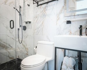 Ein modernes Badezimmer mit einer Glasdusche, einer weißen Toilette und einem Waschbecken mit Spiegel darüber.