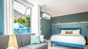 Un dormitorio moderno con un sofá gris, una cama grande con cabecera color turquesa y vistas a una piscina exterior.