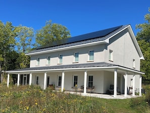 A two-story house with a covered porch and solar panels on the roof.