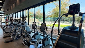 Una palestra con diverse macchine per esercizi, ampie finestre e vista sull'esterno.