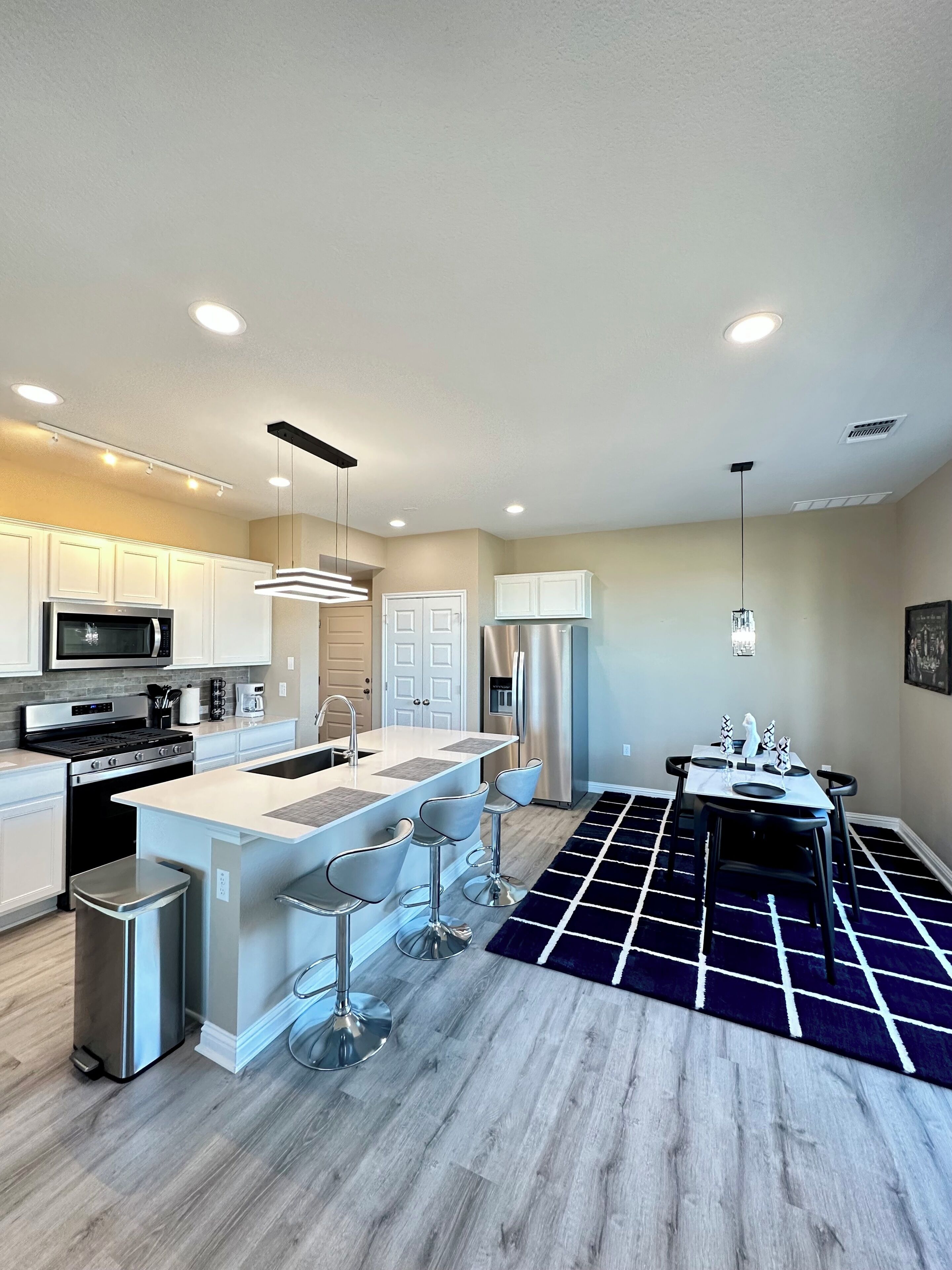 A modern kitchen with white cabinets, stainless steel appliances, and a central island with bar stools.