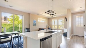 Una cucina moderna con un'isola grande, lavastoviglie integrata e un'area pranzo con tavolo e sedie.