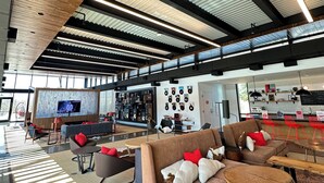 Un'ampia zona giorno con soffitto alto, arredamento moderno e schermo televisivo.