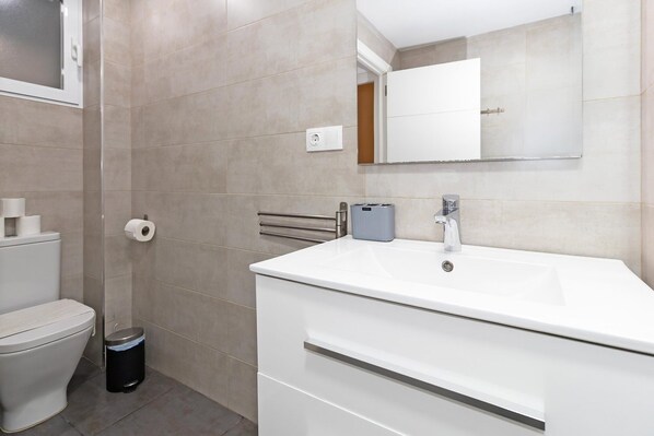 A modern bathroom with a toilet, bidet, and a sink with a mirror above it.