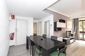 A modern dining area with a long table, chairs, and a fire extinguisher on the wall.