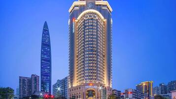 Un hotel moderno de gran altura con una torre central destacada, varios pisos y una fachada bien iluminada.