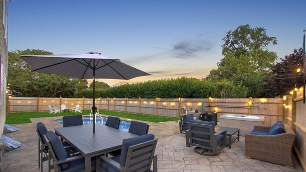Un patio al aire libre con mesa de billar, asientos y una bañera de hidromasaje.