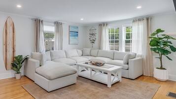 A modern living room with a sectional sofa, a coffee table, and a large window with curtains.