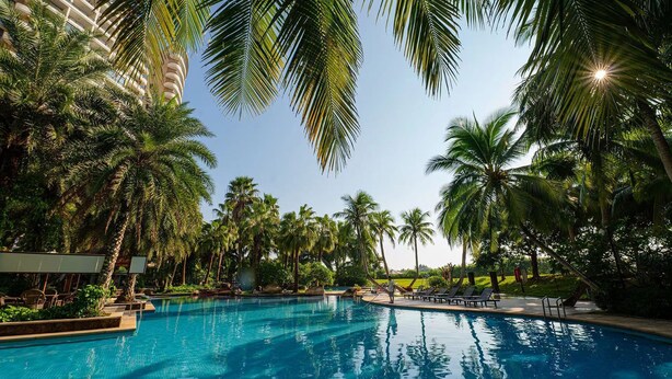 A swimming pool surrounded by palm trees and a building with balconies. - Bo'ao Heyue Seaview Hotel (Qionghai)
