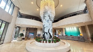 A spacious lobby with a central art installation, a reception desk, and a second-floor balcony. - Bo'ao Heyue Seaview Hotel (Qionghai)