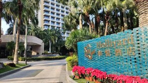 A hotel entrance with a blue mosaic sign and palm trees. - Bo'ao Heyue Seaview Hotel (Qionghai)