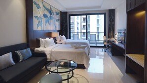 A modern hotel room with a large bed, a sofa, a glass coffee table, and a desk with a chair. - Bo'ao Heyue Seaview Hotel (Qionghai)