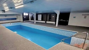 An indoor swimming pool with a blue water surface, a tiled deck, and a metal ladder. - Comfort & Peace 5Berth Family Friendly Park (St Austell)