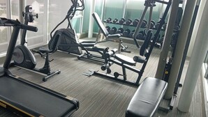 Un gimnasio con cinta de correr, elíptica y máquinas de pesas.