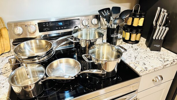 A kitchen with stainless steel pots and pans on a stove, a spice rack, and utensils. - Lake Murray 3BR Retreat with AC and Skylight (La Mesa)