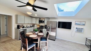 A modern kitchen with a skylight, a dining area with a round table, and a ceiling fan. - Lake Murray 3BR Retreat with AC and Skylight (La Mesa)