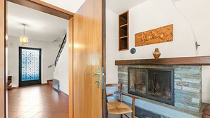 Ein Zimmer mit Kamin, Holztür, Stuhl und einer Treppe.