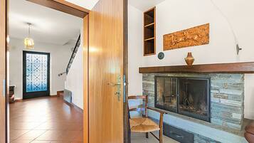 Ein Zimmer mit Kamin, Holztür, Stuhl und einer Treppe.