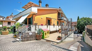 Ein zweistöckiges Gebäude mit Balkon, Treppe und einer kleinen Kinderspielecke.