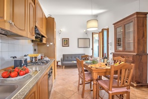 Una cocina con armarios de madera, una mesa de comedor con sillas, un sofá y una lámpara de araña.