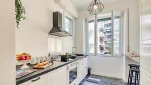 A modern kitchen with white cabinets, a black countertop, and a large window.