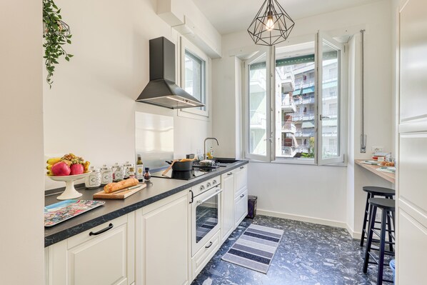 A modern kitchen with white cabinets, a black countertop, and a large window.