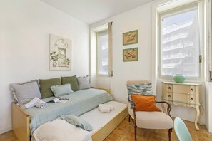 Ein Schlafzimmer mit einem Bett, einem Sessel, einem kleinen Tisch und einem Fenster.