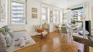 A spacious room with a bed, a dining area, and a TV.