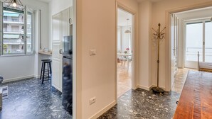 A modern kitchen with white cabinets, a black marble floor, and a wooden dining table.