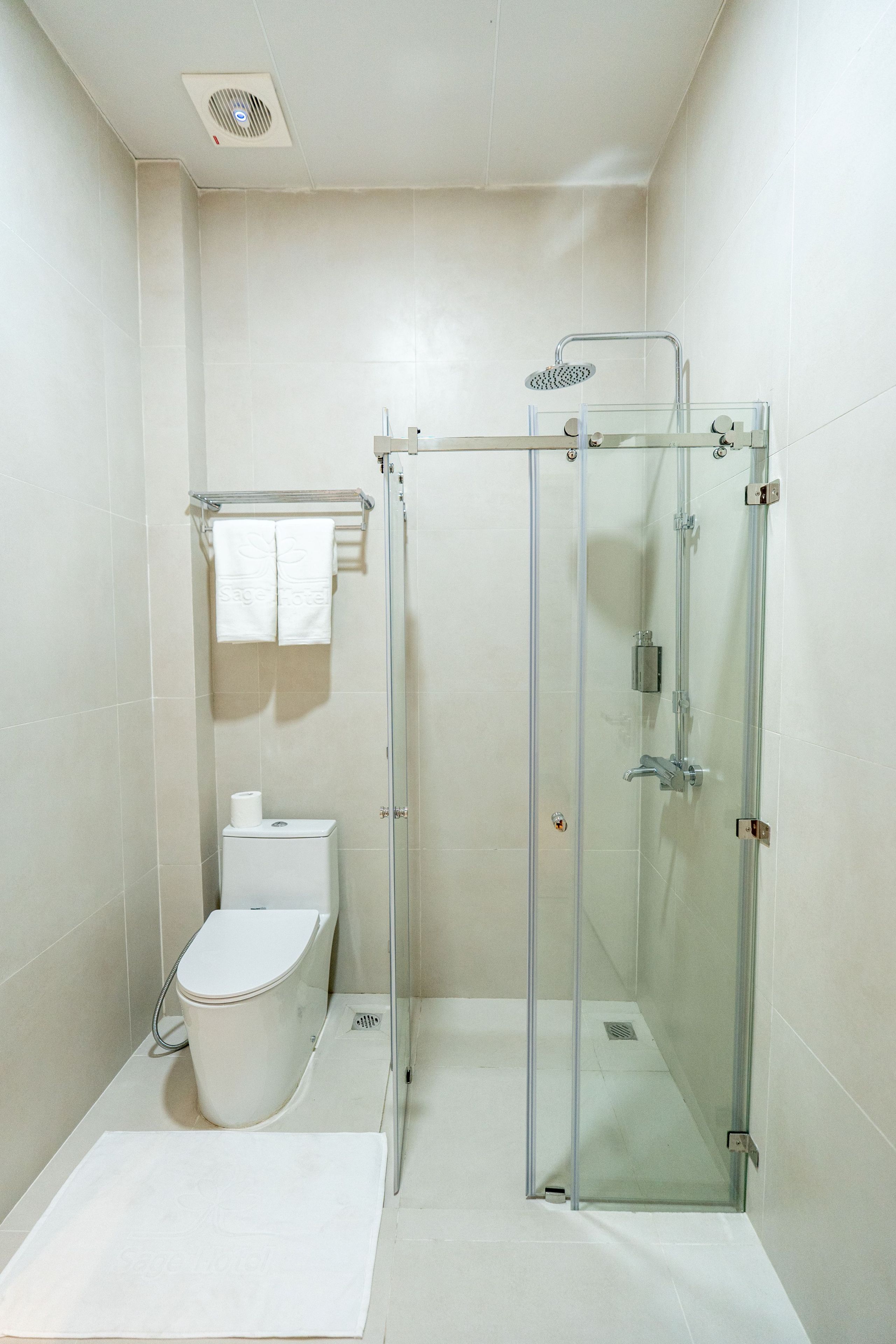 A modern bathroom with a glass-enclosed shower, a toilet, and a towel rack.