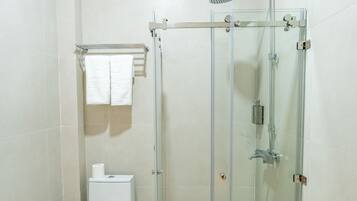 A modern bathroom with a glass-enclosed shower, a toilet, and a towel rack.