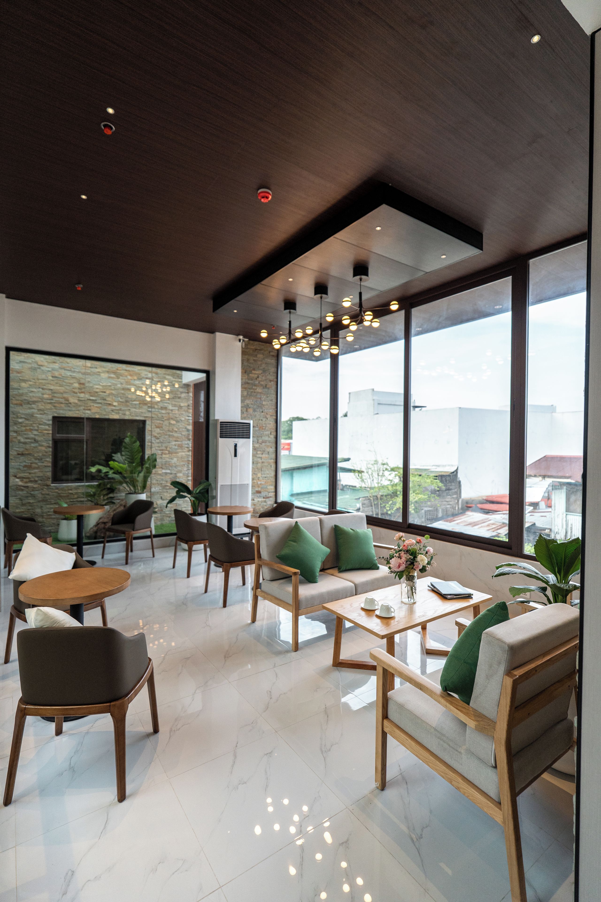 Ein modernes Interieur mit hohen Decken, großen Fenstern und einer vielfältigen Sitzmöblierung, darunter Sofas und Sessel.