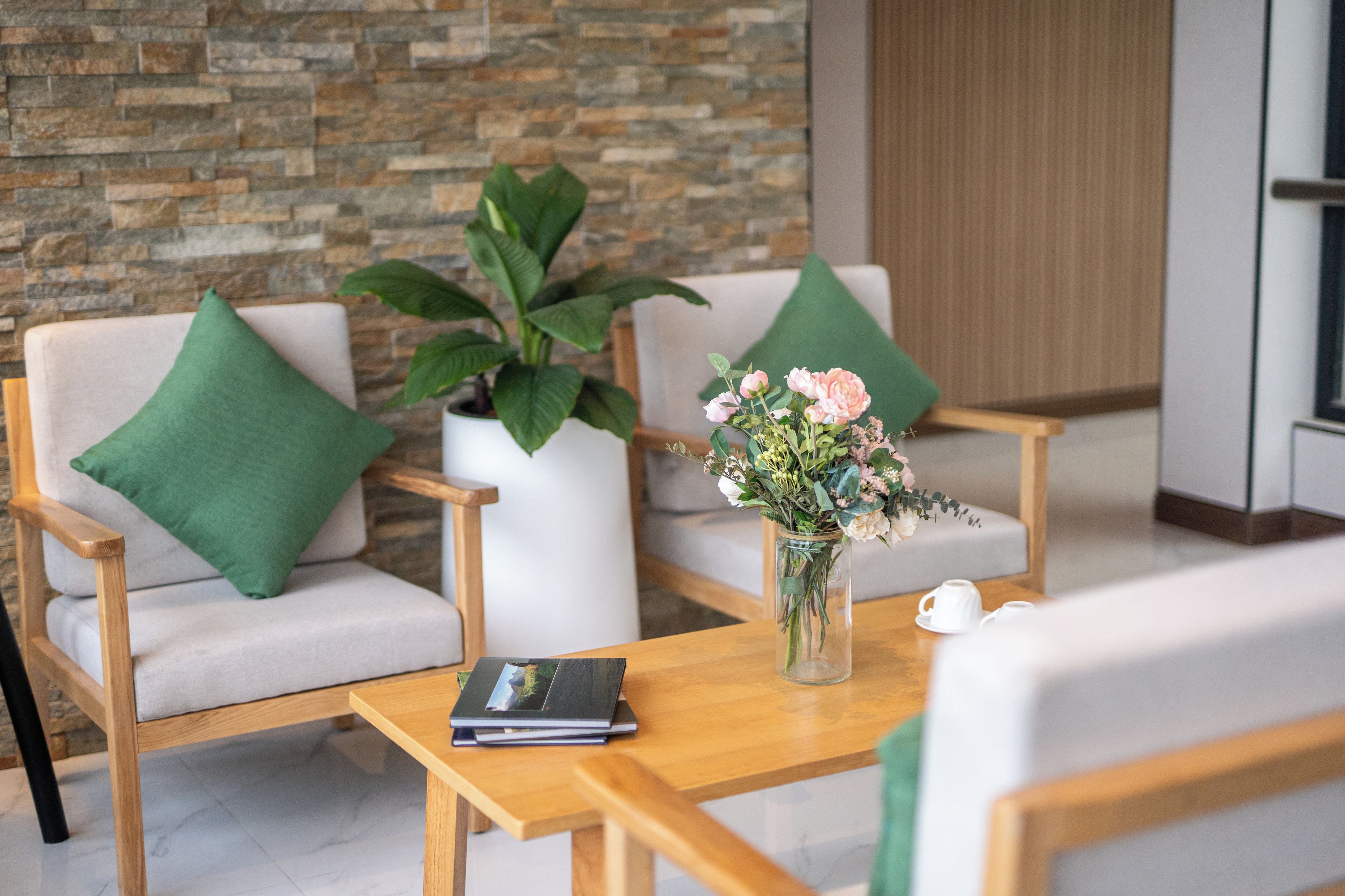 A modern lounge area with two chairs, a table, a vase with flowers, and a book.