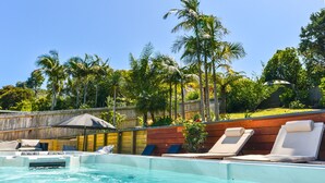 A swimming pool with lounge chairs and a wooden deck. - La Maison Soleil with heated Swim Spa (Waiheke Island)