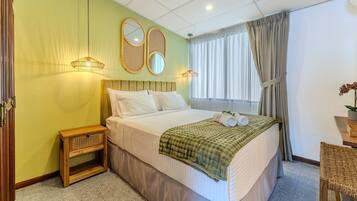 Una habitación de hotel con una cama grande, dos lámparas de noche, un espejo, una ventana con cortinas y una mesita de noche de madera.