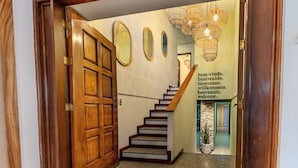 A wooden staircase with a handrail leading to a landing. There are three oval mirrors on the wall above the stairs. - Casa Lúmina - Hotel Boutique y Spa (San Salvador)