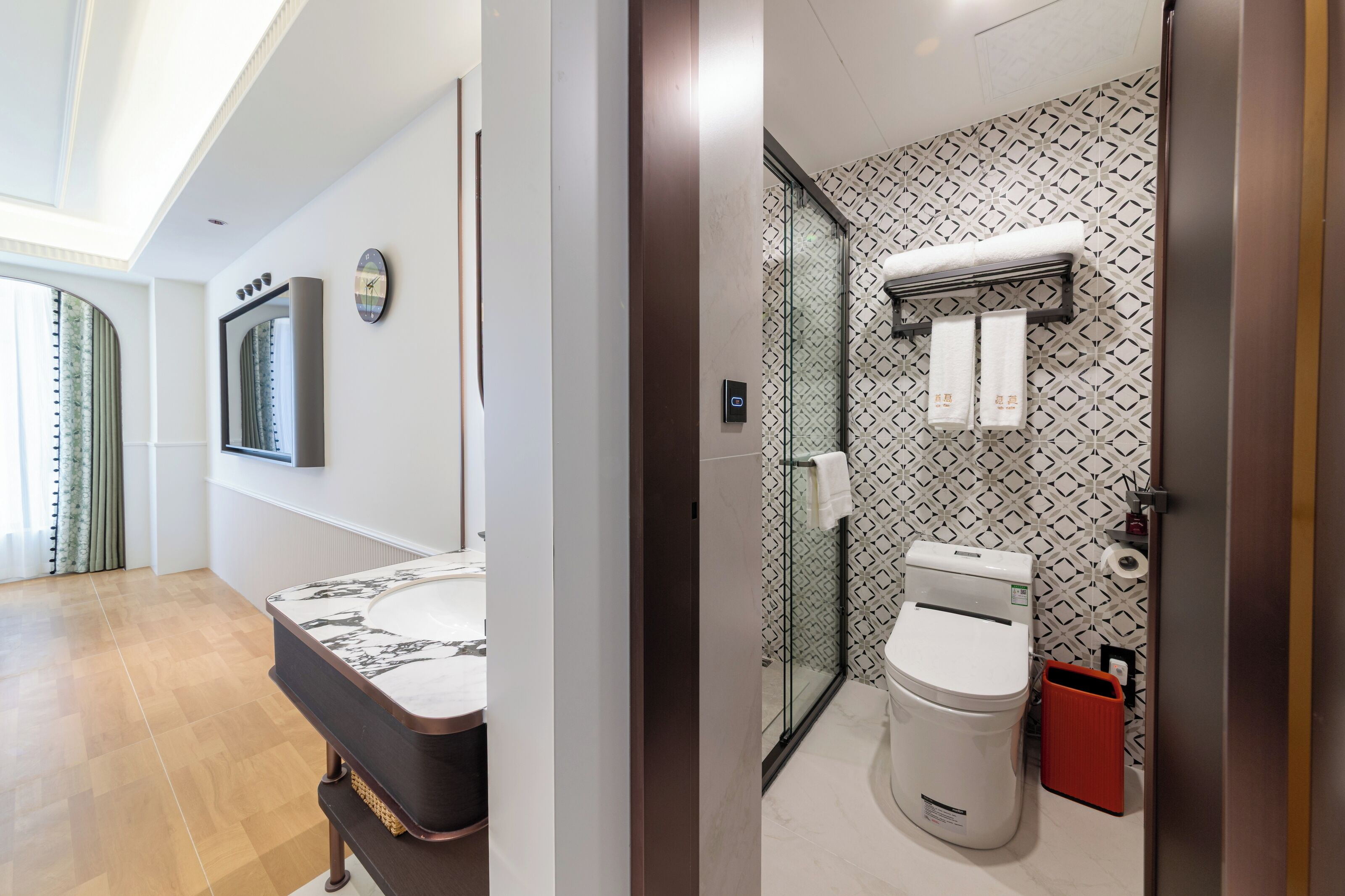 A modern bathroom with a glass shower enclosure, a toilet, and a vanity with a marble countertop.