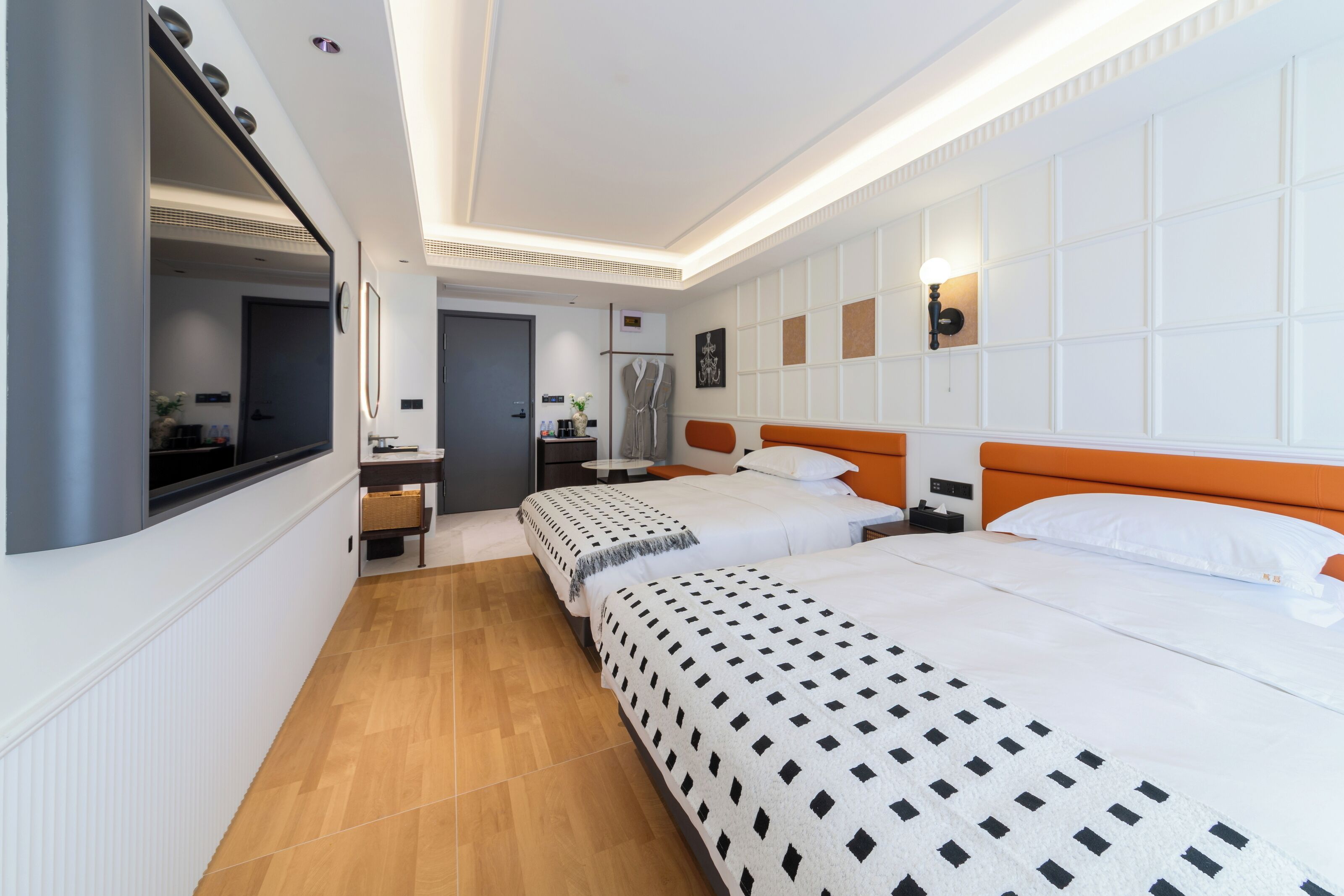 Una habitación de hotel moderna con dos camas, un espejo grande, una mesita pequeña y un armario.