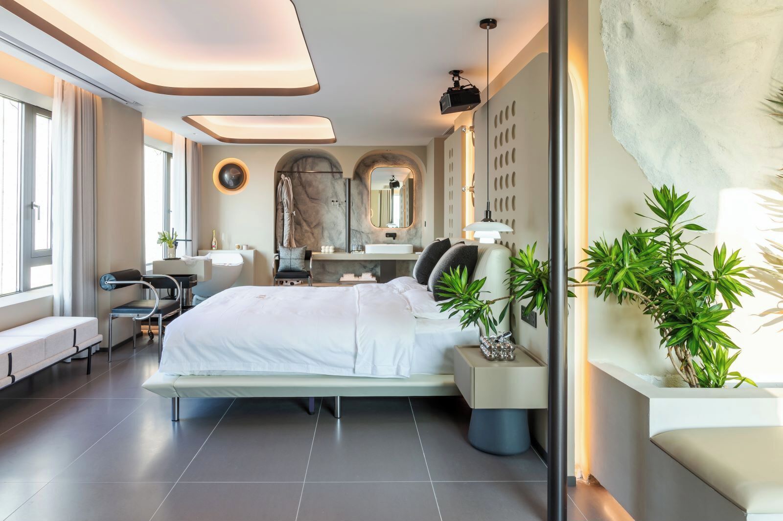 Un dormitorio moderno con una cama grande, un escritorio y una zona de estar.