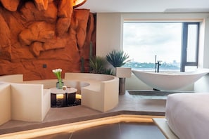A modern hotel room with a curved seating area, a large bathtub, and a city view through the window. - Niaodao Seaview Hostel (Xiamen)