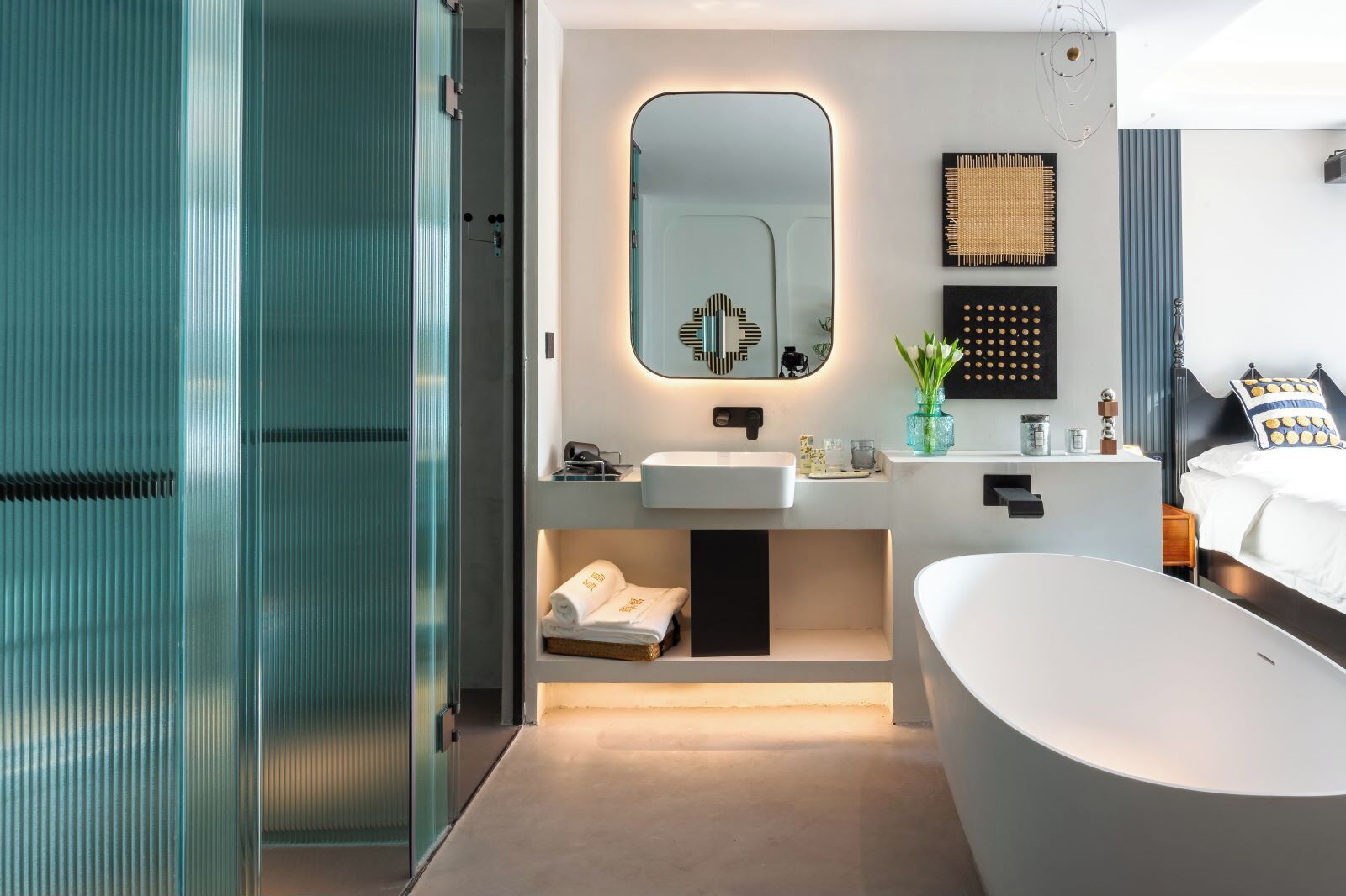 A modern bathroom with a freestanding bathtub, a large mirror, and a vanity with a sink and towel storage.