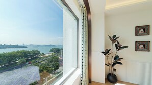 Ein Schlafzimmer mit großem Fenster, einem Blumentopf und zwei gerahmten Bildern an der Wand.