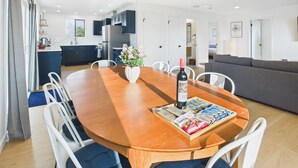 Una cocina moderna con armarios oscuros, una mesa de comedor con sillas y un área de estar con un sofá.