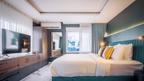 Une chambre d’hôtel moderne dotée d’un grand lit, d’une télévision, d’une armoire et d’un balcon offrant une vue sur les palmiers.